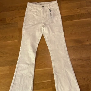 Nya Vita bootcut jeans Bootcut Winnie XS, mid waist i modell  - Snygga vita bootcut jeans från Bootcut Winnie i storlek XS. Byxorna har klassisk femficksdesign, hög midja och utsvängda ben. Tillverkade i ett mjukt bomullsmaterial som ger en skön passform. Perfekta för dig som gillar en stilren och trendig look.