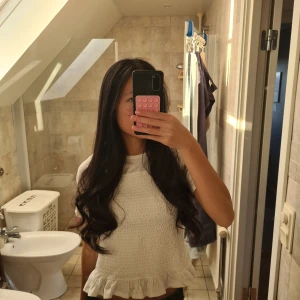 Vit blus med volang från Gina Tricot - Supersöt vit blus från Gina Tricot med korta ärmar och smockad framsida. Toppen har en rund halsringning och en volangkant längst ner som ger en gullig touch. Perfekt att styla med jeans eller kjol för en fräsch look.