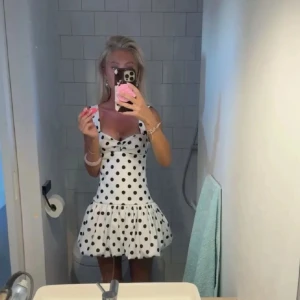 Vit prickig kort klänning med volang - Supersöt populär vit klänning med svarta prickar och volang nedtill från Zara Klänningen har breda axelband, v-ringad urringning med twistdetalj och en figurnära passform upptill. Säljer då den tyvärr inte kommer till användning, den har lappen kvar🩷🥰