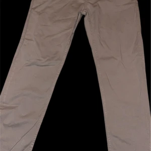 Beige chinos från Denimes - Snygga beige chinos från Denimes med klassisk rak passform och stilrena detaljer. Byxorna har två bakfickor, knapp med logga och är tillverkade i mjukt bomullsmaterial. Perfekta för en chill och clean look.