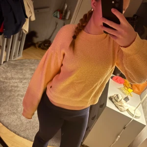 Ljusorange stickad tröja från Ü - Supermysig orange stickad tröja från Ü med breda ärmar och ribbad struktur. Tröjan har en klassisk rund halsringning.