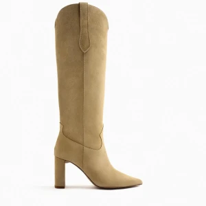 Beiga mockastövlar med klack - Säljer ett par snygga höga stövlar i beige mocka med spetsig tå och stabil blockklack. Stövlarna har en stilren western-inspirerad design och är perfekta för att lyfta vilken outfit som helst. Materialet är mjukt och ger en lyxig känsla. Använda 1 kväll