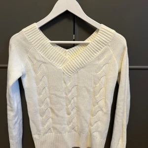 Vit stickad tröja med v-ringning Shein - Säljer en vit stickad tröja från Shein i storlek S. Tröjan har en bred v-ringning med ribbade detaljer och snyggt flätstickat mönster framtill. Perfekt för lager-på-lager och passar till både jeans och kjol.