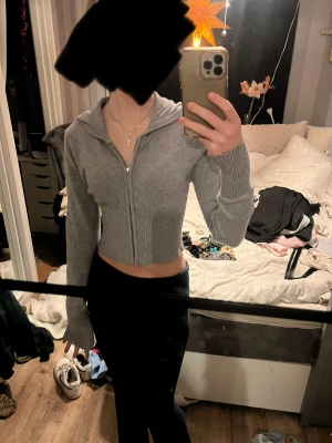  Grå stickad zip up från Gina Tricot -  En långärmad grå stickad zip up från Gina Tricot till luva. Ribbad längst ut på ärmarna och upp till bröstet medel lång