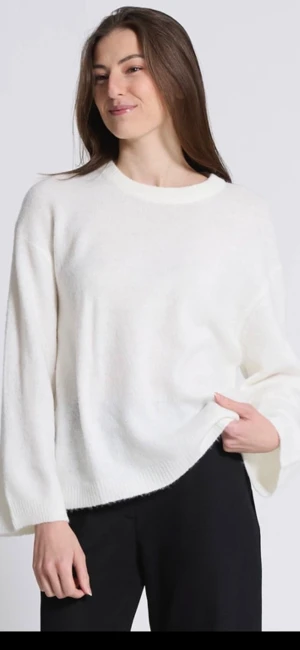 Vit stickad tröja med rund hals - Supermjuk vit stickad tröja med avslappnad passform och rund halsringning. Tröjan har långa ärmar och breda muddar vid ärmslut och nederkant. Perfekt för lager-på-lager och enkel att styla till olika outfits.