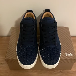 Marinblå Louboutins - Säljer ett par fina Mörkblåa skor med spikar, Dustbag och box ingår samt extra spikar och kort! Hör gärna av er med frågor. Använt ett par gånger men fortfarande riktigt bra skick!