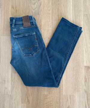 Blå Replay Anbass W30 - Jag säljer dom här riktigt snygga blå Replay Anbass jeansen som är i storlek W30. De är upplagda så utgå ifrån måtten. Dom är i fint skick utan skador. Tveka inte att höra av er!                 Mått: Längd=95cm. Midja=36cm