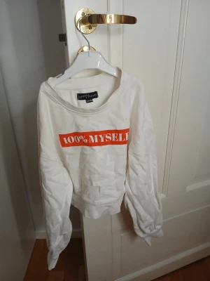 Vit sweatshirt XOXO Friends 100% Myself - Vit sweatshirt från XOXO Friends med trycket '100% MYSELF' i rött framtill. Tröjan har rund hals, långa ärmar och en avslappnad passform. Perfekt för dig som vill ha en enkel men cool stil.