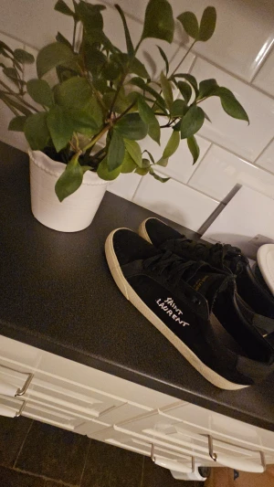 Saint Laurent svarta sneakers - Svarta sneakers från Saint laurent. Stilren, minimalistisk design som passar till många outfits. Dom har spruckit lite i sidorna men funkar som vilka andra skor som helst 