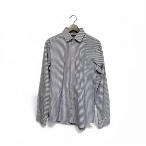 Blåvit randig skjorta Tiger of Sweden - Snygg blåvit skjorta från Tiger of Sweden i storlek 40. Skjortan har klassisk krage, vertikala ränder och knappar framtill. Tillverkad i mjuk bomull med lång ärm och stilren look. Perfekt för dig som gillar clean och fräsch stil.