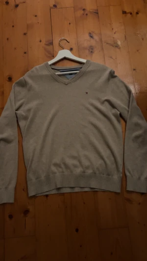 Tommy Hilfinger -  En beige stickad Tommy Hilfinger I storleken M men passar också S. Den är i fint skick inte sönder eller tydligt slitage