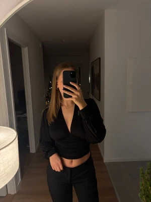 Svart omlott croppad topp - Säljer en svart topp från Nelly i storlek xs. Väldigt bra skick!