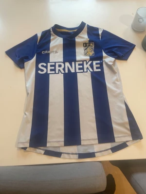 IFK Göteborg matchtröja Craft blå/vit - En jättefin ifk tröja som är hundra procent riktig. Båda loggorna på vänster sida och på högersidan är lite slitna i tvätten efter 3 år men annars en jättefin fotbollströja.