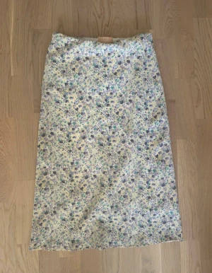 Kjol från Love Triangle - Säljer kjol från Love Triangle i storlek XS. Midilång rak modell med resår i midjan. Småblommigt mönster: gul botten med lila/blå/ gröna toner. Använd vid ett tillfälle mycket bra skick Kategori Varumärke Storlek Skick Färg Midikjolar