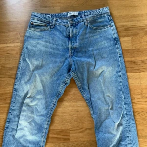 Jack & Jones Loose Jeans Blå 33/30 - Snygga ljusblå jeans från Jack & Jones i loose fit-modell. Klassisk femficksdesign med raka ben och slitna detaljer för en avslappnad vibe. Tillverkade i bomull med tvättad finish och midwaist. Perfekta för dig som gillar bredare passform och streetstil.