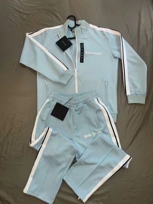 Palm Angels ljusblå mjukisbyxor - Snygga ljusblå mjukisbyxor från Palm Angels med vita och svarta ränder längs med kanten.