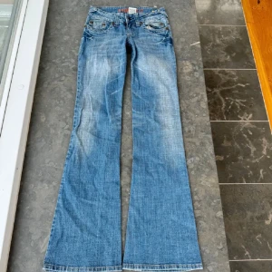 Blå bootcut jeans från Hydraulic - Snygga blå bootcut jeans från Hydraulic med slitna detaljer och broderade bakfickor. Fanns ett hål på baksidan då ”skärphållaren” gått sönder men jag har lagat det så att det inte syns på samma sätt (se bild 6) Midjemåt: 37 Innerbenslängd: 83! Skriv vid frågor❣️