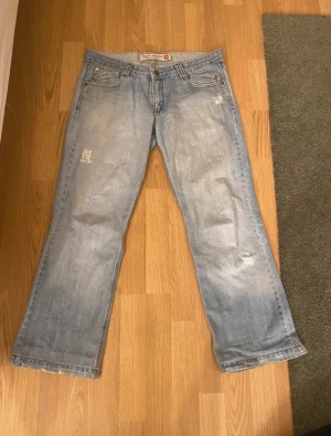 Diesel ljusblå bootcut jeans - Säljer ett par ljusblå jeans från Diesel med klassisk bootcut passform. Jeansen har slitna detaljer, fem fickor och snygga sömmar. Baktill finns Diesel-logga på fickan och coola bälteshällor. Perfekt för dig som gillar avslappnad stil.