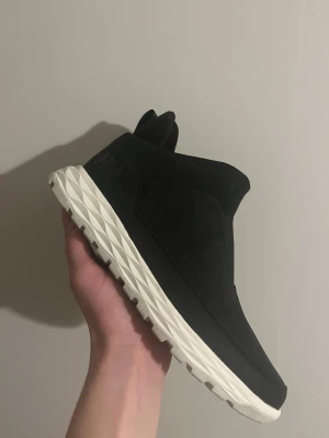 Helly Hansen - Boots från Helly Hansen i svart med vit, mönstrad sula. Vattentäta och med Ortholite innersula för extra komfort. Snygg minimalistisk design med rund tå och platt sula, tillverkade i syntetmaterial. Perfekta för höst och vinter.