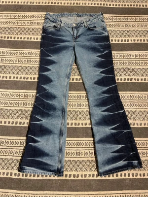 Bootcut jeans med mönster  - Säljer ett par blå jeans från Weekday med riktigt coolt batikmönster i mörkare och ljusare toner. Modellen är bootcut jeans. Säljer pga fel storlek.💓