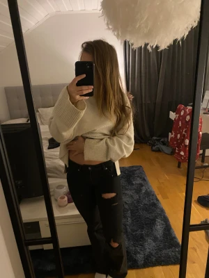 Svarta jeans med slitningar - Säljer ett par svarta jeans med snygga egengjorda slitningar på benen. Byxorna har en klassisk femficksdesign och raka ben med lätt bootcut. Perfekt för dig som gillar en cool och avslappnad look. 