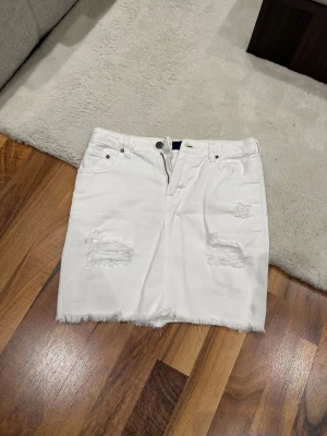 Vit jeanskjol  - Jättesöt jeanskjol med slitningar från Nelly. Står ingen storlek i kjolen, men passar mig som har XS.