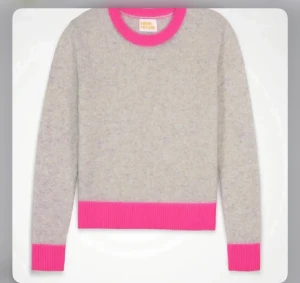 Grå stickad tröja med rosa detaljer - Supersnygg grå stickad tröja från From Future med ribbade rosa kanter vid hals, ärmslut och nederkant. Mjuk och skön, perfekt för dig som gillar färgklickar. Rund hals och långärmad modell som är enkel att matcha med jeans eller kjol. 100% Kashmir och är i samma färg som första bilden.