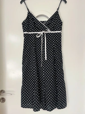 Svart prickig klänning med rosett - Superfin pricking klänning med snöre. Passar s-m. 