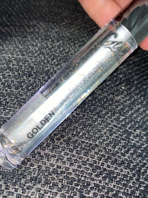 Golden Shimmer Lipgloss från Gurl - Transparent läppglans med gyllene glitterpartiklar från Gurl. Kommer i en smal tub med svart lock och har en skimrande finish som ger läpparna extra glans och lyster. Perfekt för dig som vill ha en glittrig touch på läpparna.