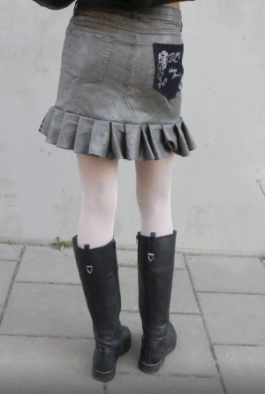 Emmie Kjol - Silver kjol med volang och svarta detaljer.                  Storlek: midja-72cm stuss-87cm 