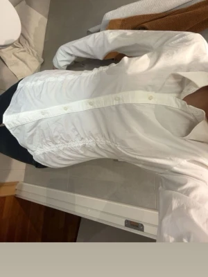 Vit skräddar skjorta med rynkade sidor - Klassisk vit skjorta med figurnära passform och snygga rynkade detaljer längs sidorna. Skjortan har långa ärmar, krage och knäppning framtill. Konstig storlek och passar mig som har xs/s