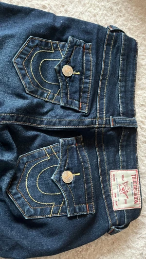 True Religion Joey bootcut jeans blå - Säljer ett par mörkblå True Religion Joey jeans med bootcut och låg midja. Använt ett par gånger nytt pris ungefär 1200. Bra skick skriv för frågor eller fler bilder