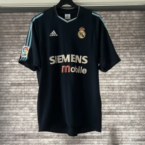 Real Madrid 2003/2004 - Real Madrid 2003/2004 borta ställ!! Bra skick men det finns slitage på sponsorn.  Skriv till mig vid funderingar eller mer bilder😁🤩