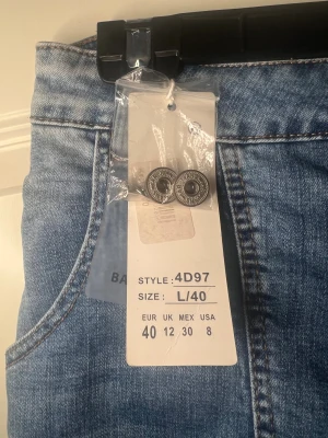 Blå skinny jeans med knappar, L/40 - Snygga blå jeans med slitna detaljer och flera knappar framtill. Modellen är skinny med hög midja och klassiska bakfickor. Jeansen har en cool tvättad look (fattas två knappar på byxan men medföljer två extra) helt nya oanvända jeans