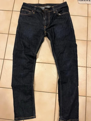Mörkblå jeans från Nudie Jeans, 29/30 - Säljer ett par mörkblå jeans från Nudie Jeans i storlek 29/30. Ett par stilrena jeans som passar bra till allt. Dem är i mycket bra skick. Pris står inte hugget i sten och kan diskuteras vid snabb affär😃