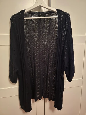 Mörkblå spetskofta från H&M strl. XS/S - Mörkblå, öppen spetskofta från H&M med vackert virkat mönster. Koftan har trekvartsärmar och är perfekt att slänga över en topp för en chill och stilren look. Lätt och luftig.