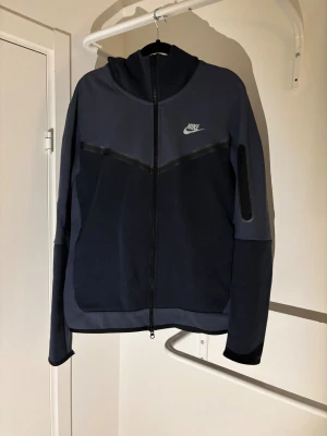 Mörkblå Nike tech - Säljer nu en Nike tech i färgen thunder blue. Storlek M. Skick 8/10 Inga defekter så som hål eller liknande. Riktigt skön och snygg tröja. Kontakta mig om du har frågor ;)