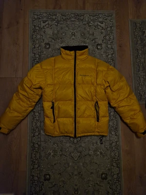 Vintage Peak Performance - Säljer en vintage gul pufferjacka från Peak Performance. Varm och skön, passar perfekt för vintern❄️ Vänstra fickan har blixtlåset hoppat ur.