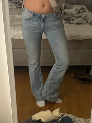 Bootcut ljusblå jeans - Säljer ett par ljusblå bootcut jeans från  med klassisk femficksdesign och låg midja. Jeansen har en snygg tvättad look och är tillverkade i mjukt denimtyg som sitter skönt. Perfekt passform med lite utsvängda ben för en chill vibe.