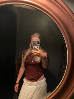 Mörkröd ärmlös linnetopp - Säljer en stilren mörkröd linnetopp med rund hals och ärmlös design. Toppen har en tight passform och är tillverkad i ett mjukt material som sitter skönt mot kroppen. Perfekt att matcha med både kjol och jeans för en snygg look.