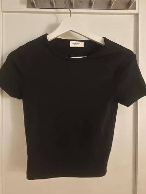 Svart basic t-shirt från Gina Tricot - En svart, enkel och stilren t-shirt från Gina Tricot, basically basics-kollektionen. T-shirten har rund halsringning och korta ärmar. 