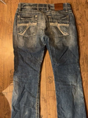 Jeans från Camp David  - Säljer ett par blå jeans från Camp David med tydliga kontrastsömmar och unika broderade detaljer på fickorna. Dom är i superbra skick och har inga slitningar. Det står ingen storlek men jag skriver mått, skulle säga att dom passar M.                  midjemått tvärs över : 42 cm                         innerbenslängd : 76 cm                                  ytterbenslängd : 100 cm