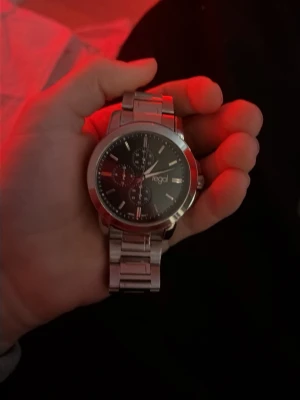 Regal klocka - Snygg regal   klocka  med  länkarmband och svart urtavla. Klockan har tre mindre urtavlor och tydliga markeringar. Stilig accessoar som passar till många olika stilar