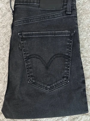 Svarta Levi's Mile High Super Skinny jeans W27L30 - Säljer ett par svarta Levi's Mile High Super Skinny jeans med hög midja och klassisk femficksdesign. Jeansen är i stretchigt denim och har smal passform hela vägen ner. Perfekta till sneakers eller boots.
