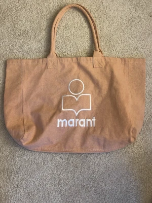 Beige shoppingväska från Marant - Rosa shoppingväska från Marant i bomull med dubbla handtag och vit logotyp framtill. Enkel och stilren design som passar till det mesta.PRIS KAN DISKUTERAS!!🥰