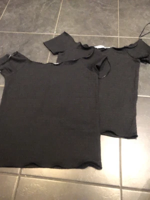 Svarta ribbade toppar med kort ärm - Två svarta ribbade toppar med kort ärm och rund halsringning. Tidlös och enkel design som passar till det mesta. Perfekt basplagg i garderoben. Säljer den som har Xs för 50 och den som har S 70 och 100 om ni vill köpa båda.