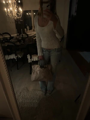 Vit topp - Supersnygg vit topp med lång ärm och ribbad struktur. Toppen har en bred, rund ringning och sitter tight för en modern och fräsch look. Perfekt att matcha med jeans för en trendig outfit.