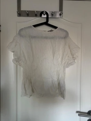 Vit blus med smock  - Säljer en vit blus med volangärmar och har smock i midjan, storlek M, inga defekter (inga hål, fläckar osv) från H&M!
