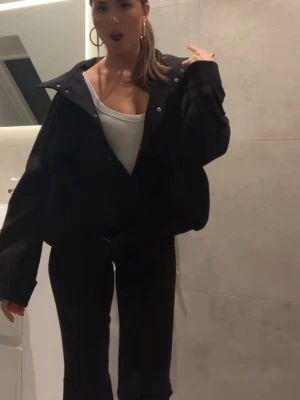 Svart jacka med tillhörande skärp - Svart jacka. Finns ett bälte fast i jackan. Älskar detaljerna på denna. 