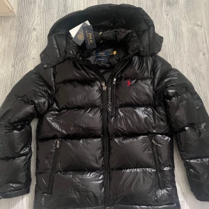Ralph lauren jacka - Hej! En glossy Ralph lauren jacka till salu. Jackan är i jättebra skick och den har inga defekter elller tecken av användning. Jackan är köpt på Nk och kvittot finns kvar. Jag säljer jackan pågrund av att den tyvärr inte passar mig, priset kan diskuteras lite vid snabbaffär. hör av dig vid frågor 😁